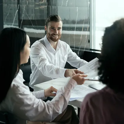 Tres personas revisan documentos en una mesa de trabajo